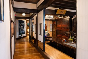 A traditional Japanese interior with wooden floors, tatami mats, and a reception desk. - Kappo Ryokan Uoichi (Shimada)