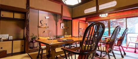A traditional Japanese room with tatami flooring, a wooden dining table, and chairs.