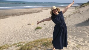 A beach with a person in a blue dress and straw hat. - Kappo Ryokan Uoichi (Shimada)