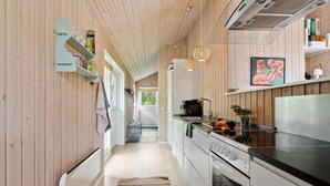 A modern kitchen with wooden walls, a central island, and a dining area with a view.