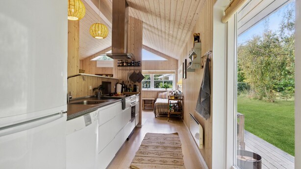 A modern kitchen with wooden accents, a central island, and a view of the outdoors.