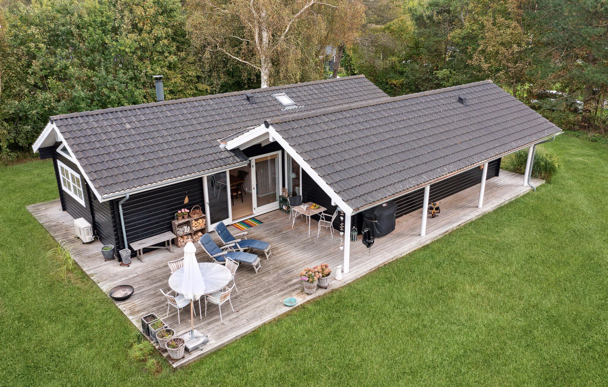 A two-story house with a covered deck, a patio with outdoor furniture, and a garage.