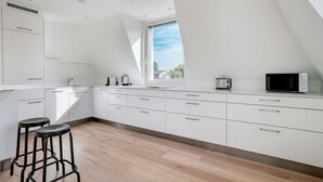 Una cocina moderna con armarios blancos, una ventana y un microondas.