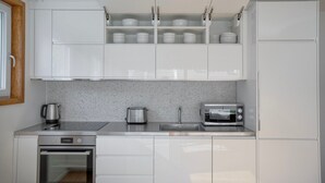 A modern kitchen with white cabinets, a stainless steel countertop, a toaster, a kettle, and a microwave. - Nice Wallisellen 2br w/ Storage & W/D, nr Local Market, by Blueground (Zurich)