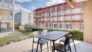 A modern apartment building with balconies, a patio with a table and chairs, and a clear sky. - Nice Wallisellen 2br w/ Storage & W/D, nr Local Market, by Blueground (Zurich)
