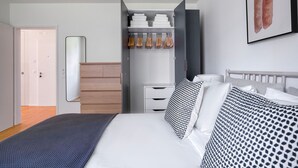 A modern bedroom with a bed, bedside tables, a wardrobe, and a mirror. - Nice Wallisellen 2br w/ Storage & W/D, nr Local Market, by Blueground (Zurich)