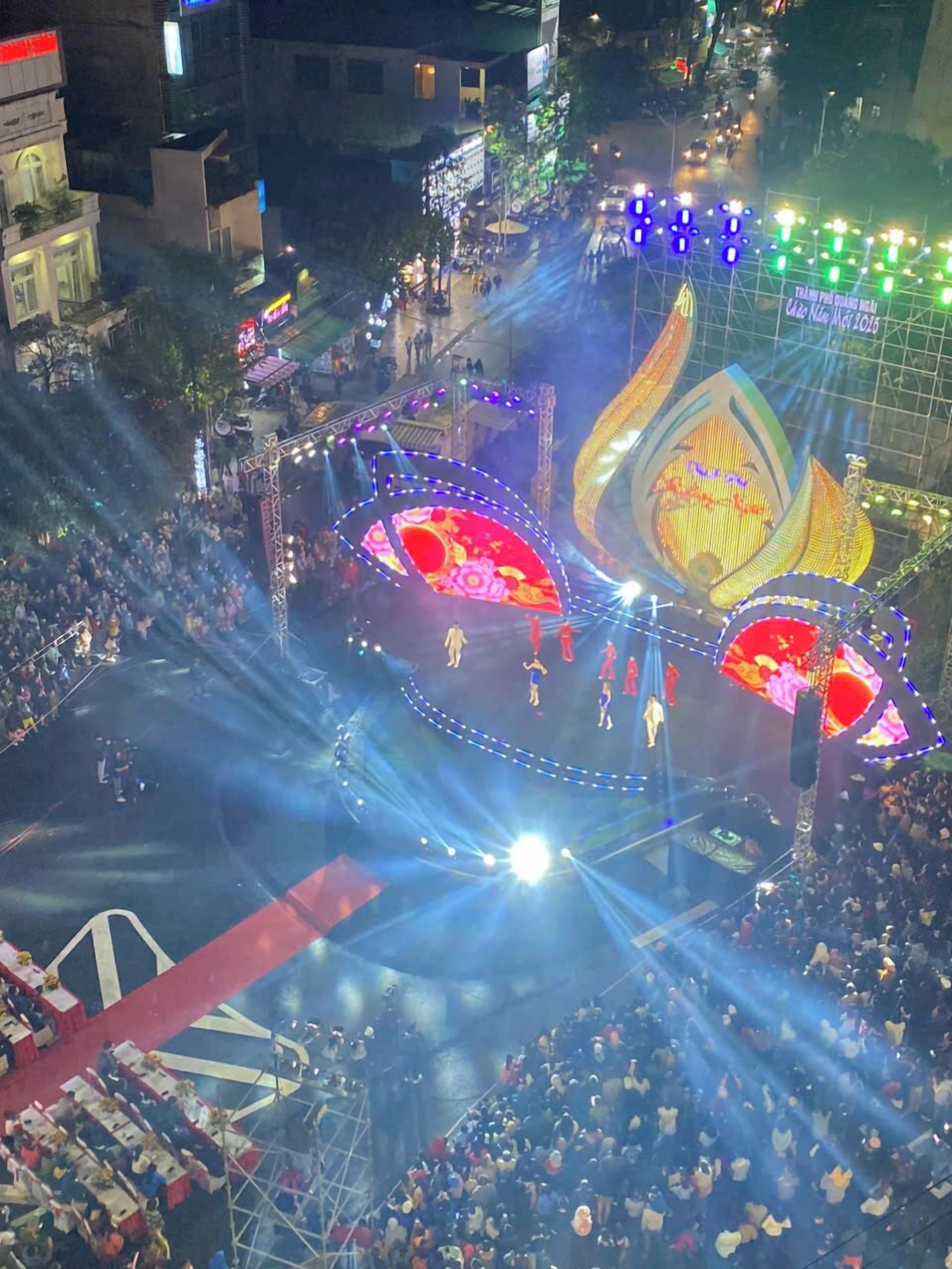 A large outdoor event with a stage, audience, and illuminated structures.