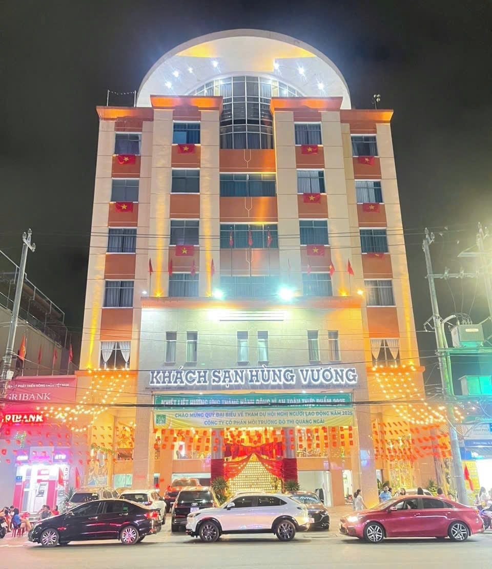Un hotel de varios pisos con un cartel llamativo que dice "KHACH SAN HUNG VUONG".