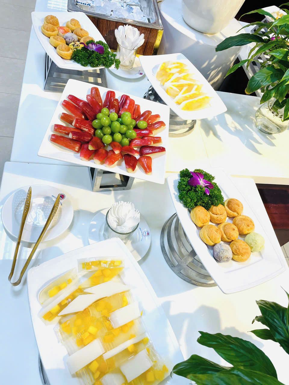 A buffet table with various food items including pastries, fruits, and a dish with yellow cubes.