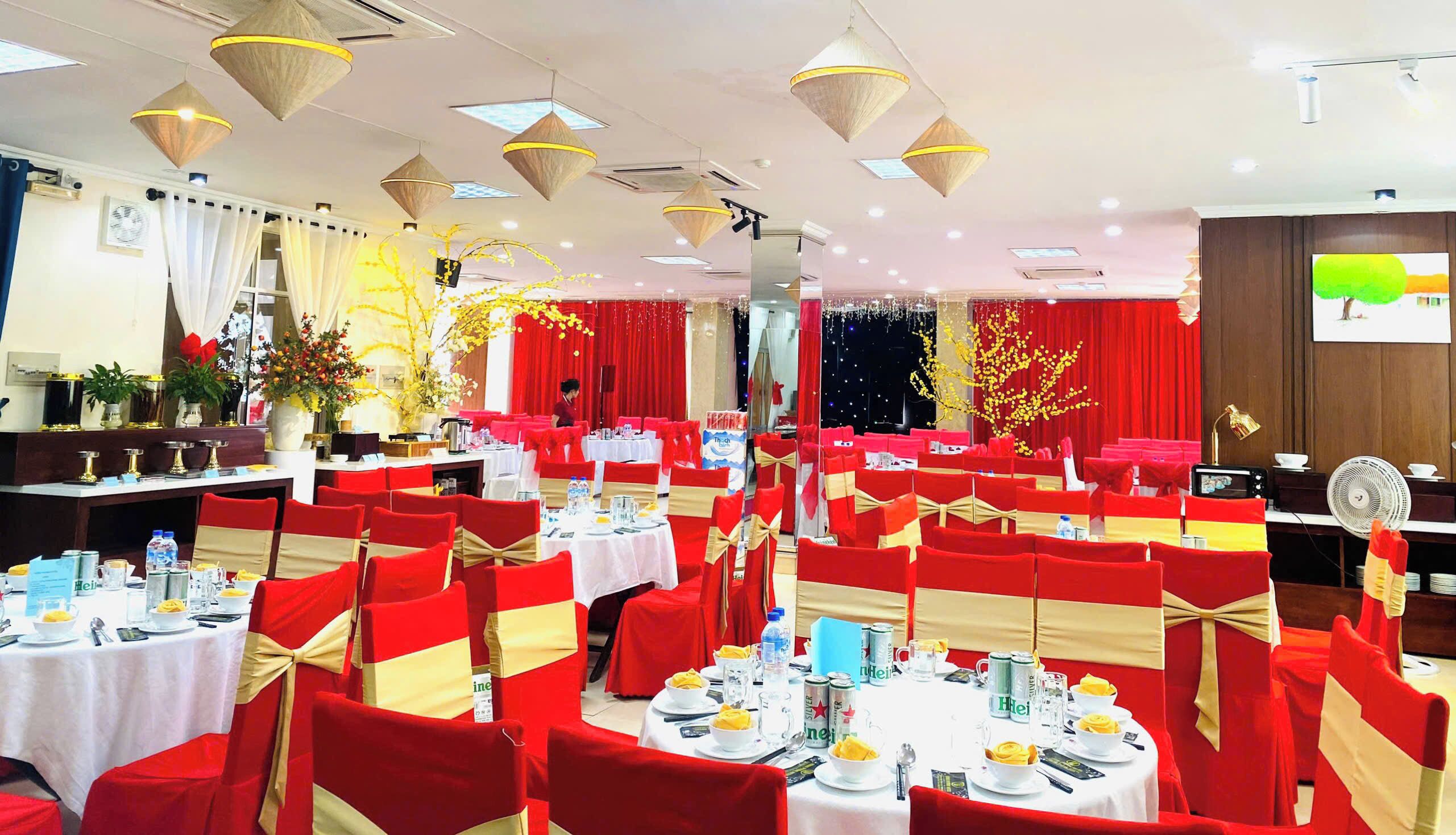 A banquet hall with round tables, red chairs, and gold sashes.