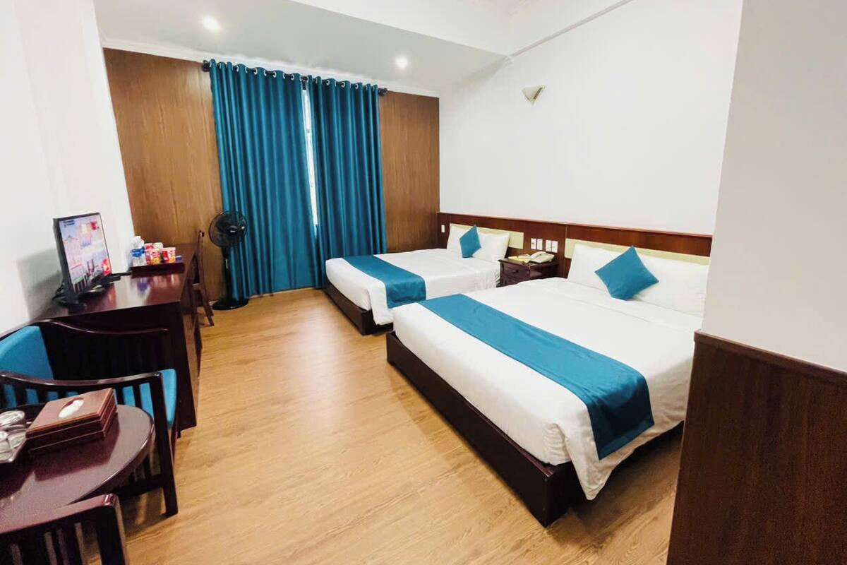 Habitación de hotel con dos camas, un escritorio y una silla.