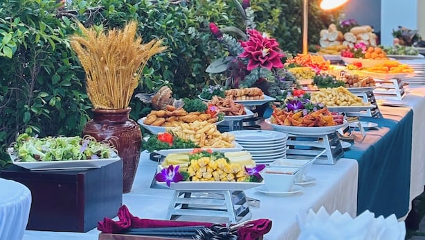 Een buitenbuffet met diverse gerechten en decoratieve planten.