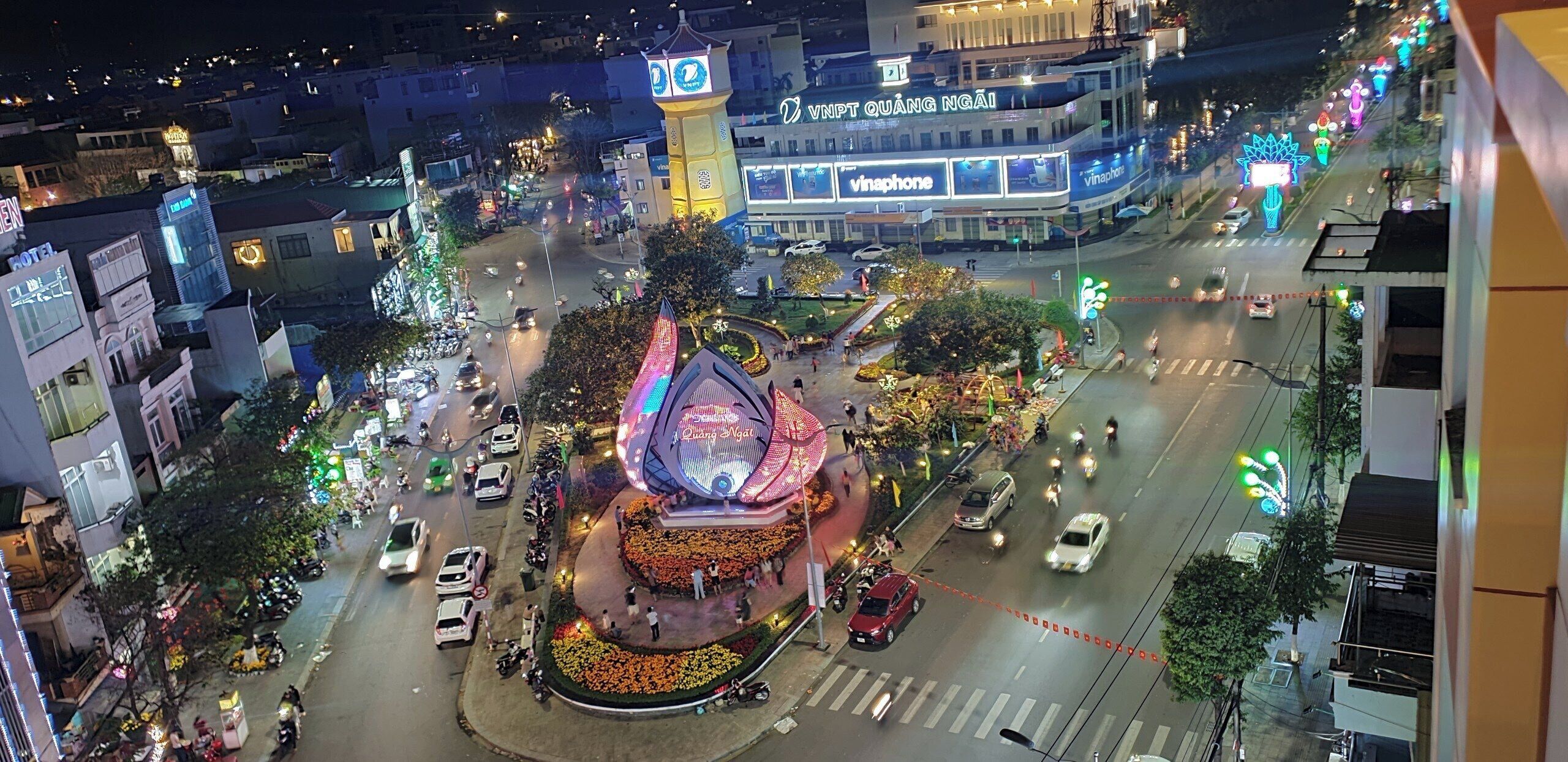 A hotel with a prominent tower and signage, surrounded by a busy street with vehicles and pedestrians.