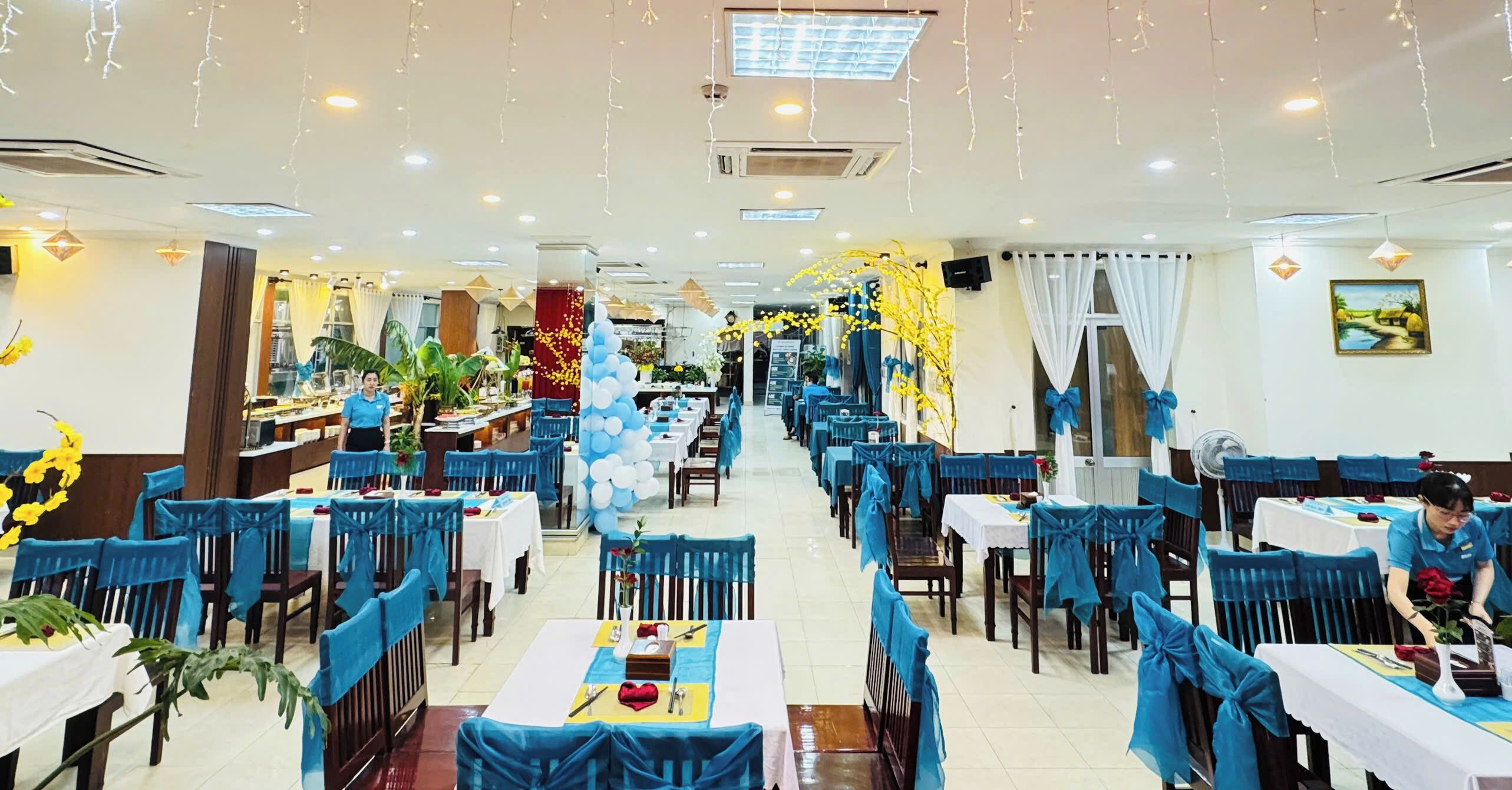 Un restaurant spacieux avec des chaises et des tables bleues, décoré de ballons et de guirlandes lumineuses.