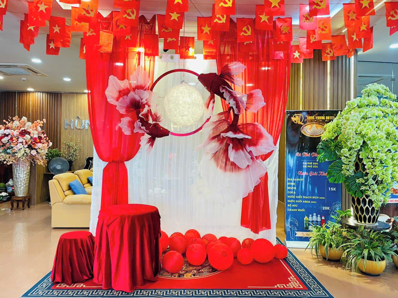 Un espacio interior decorado con una paleta de colores rojo y blanco, que incluye una lámpara central circular, cortinas rojas y un arreglo floral.