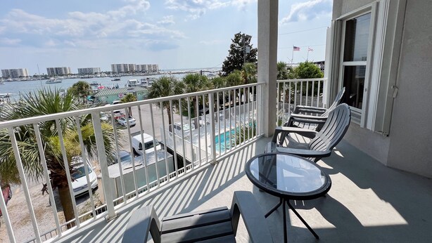 Ein Balkon mit Blick auf die Marina und die umliegenden Gebäude, ausgestattet mit zwei Liegestühlen und einem kleinen Tisch.