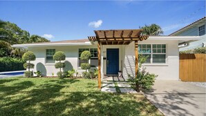 A residential house with a well-maintained lawn, a wooden pergola, and a front door. - Minutes to Palm Beach and Downtown WPB 3 br villa with pool! (West Palm Beach)