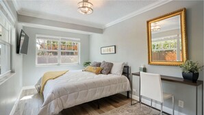 A bedroom with a bed, bedside table, chair, and a large mirror. - Minutes to Palm Beach and Downtown WPB 3 br villa with pool! (West Palm Beach)