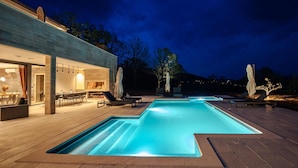 A modern outdoor pool area with a wooden deck, lounge chairs, and umbrellas. - Cozy home in Cista Velika with sauna (Cista Velika)