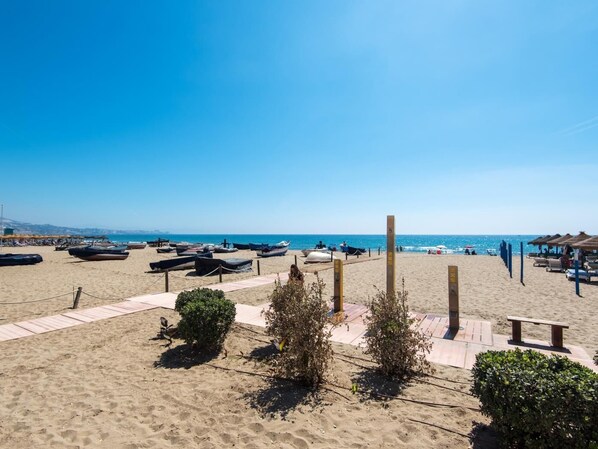 A beach with sun loungers, umbrellas, and boats. - BOLICHES CENTER APARTMENT next to the BEACH (FUENGIROLA)