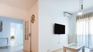 Una sala de estar moderna con una televisión de pantalla plana montada en la pared, una mesa de centro de vidrio y un sofá.