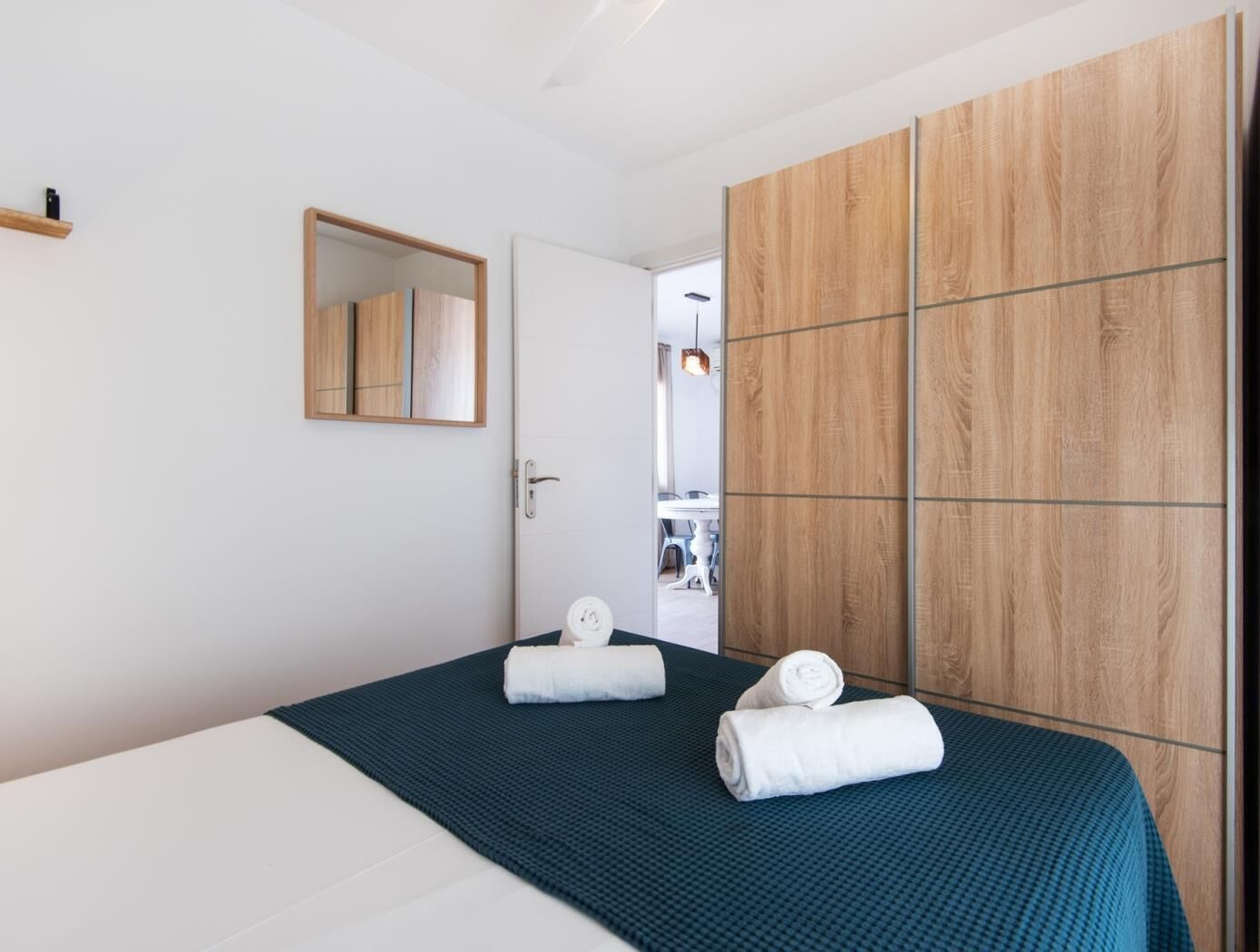 Una moderna camera d'albergo con un letto, un armadio in legno, uno specchio e vista sulla sala da pranzo.