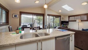 A modern kitchen with a large island, double sink, and pendant lighting.