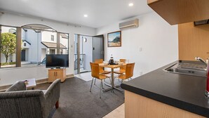Een compacte woonruimte met kitchenette, eethoek en televisie in de woonkamer.
