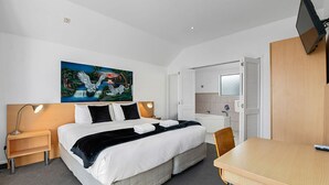 Een hotelkamer met een bed, nachtkastjes, een bureau, een stoel, een schilderij, een badkuip en een televisie.