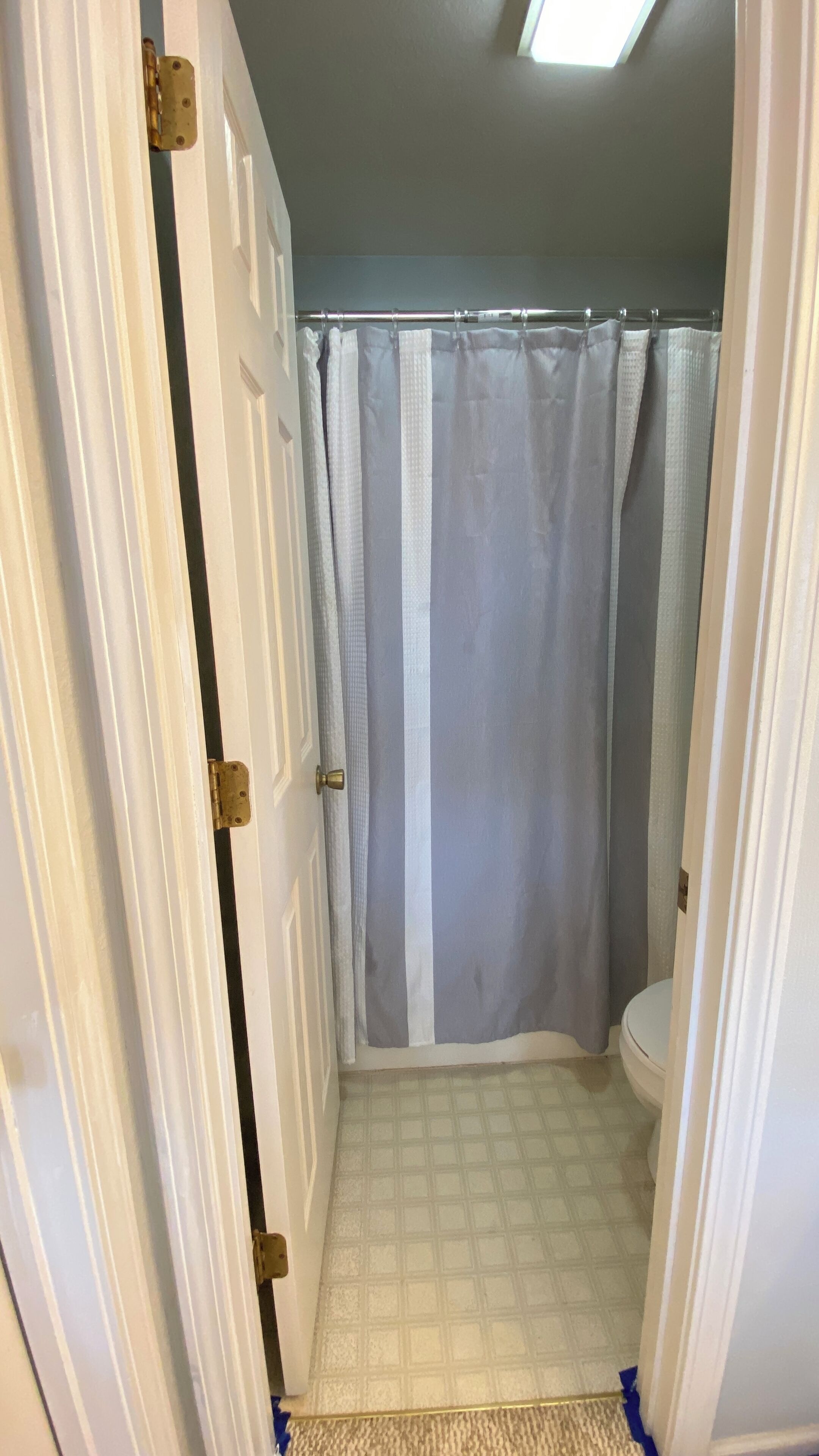 A bathroom with a shower curtain, toilet, and patterned floor tiles.