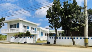 A two-story white building with blue accents, a gated entrance, and a clear sky. - AZZURRA (Miyakojima)
