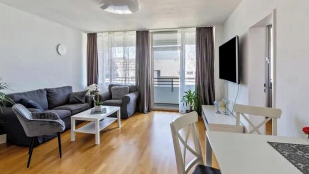 A modern living room with a sofa, coffee table, and dining table. - Cozy Neuss Apartment with Modern Amenities (Neuss)