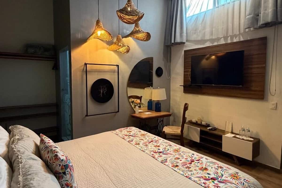 A modern bedroom with a large bed, a TV mounted on the wall, and a ceiling light fixture.