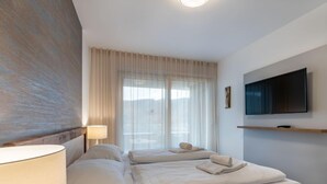 Una camera d'albergo moderna con un letto grande, una TV a parete e una finestra con tende.