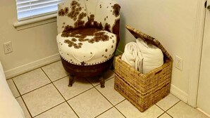 Une pièce avec une fenêtre, une chaise, un tableau et un panier.