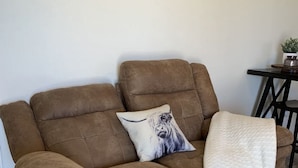 Un canapé marron avec un plaid blanc et un coussin orné d’une image de chien.