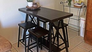 Un petit coin repas avec une table en bois foncé et deux chaises assorties. On peut voir une plante en pot et un petit récipient sur la table.