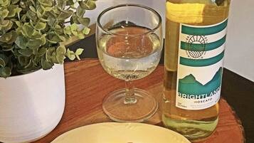A bottle of Brightlands Moscato wine, a glass of water, and a plate with green and white grapes on a wooden table.