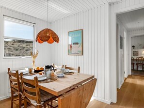 Un comedor con una mesa de madera, sillas, una lámpara colgante y un cuadro en la pared.