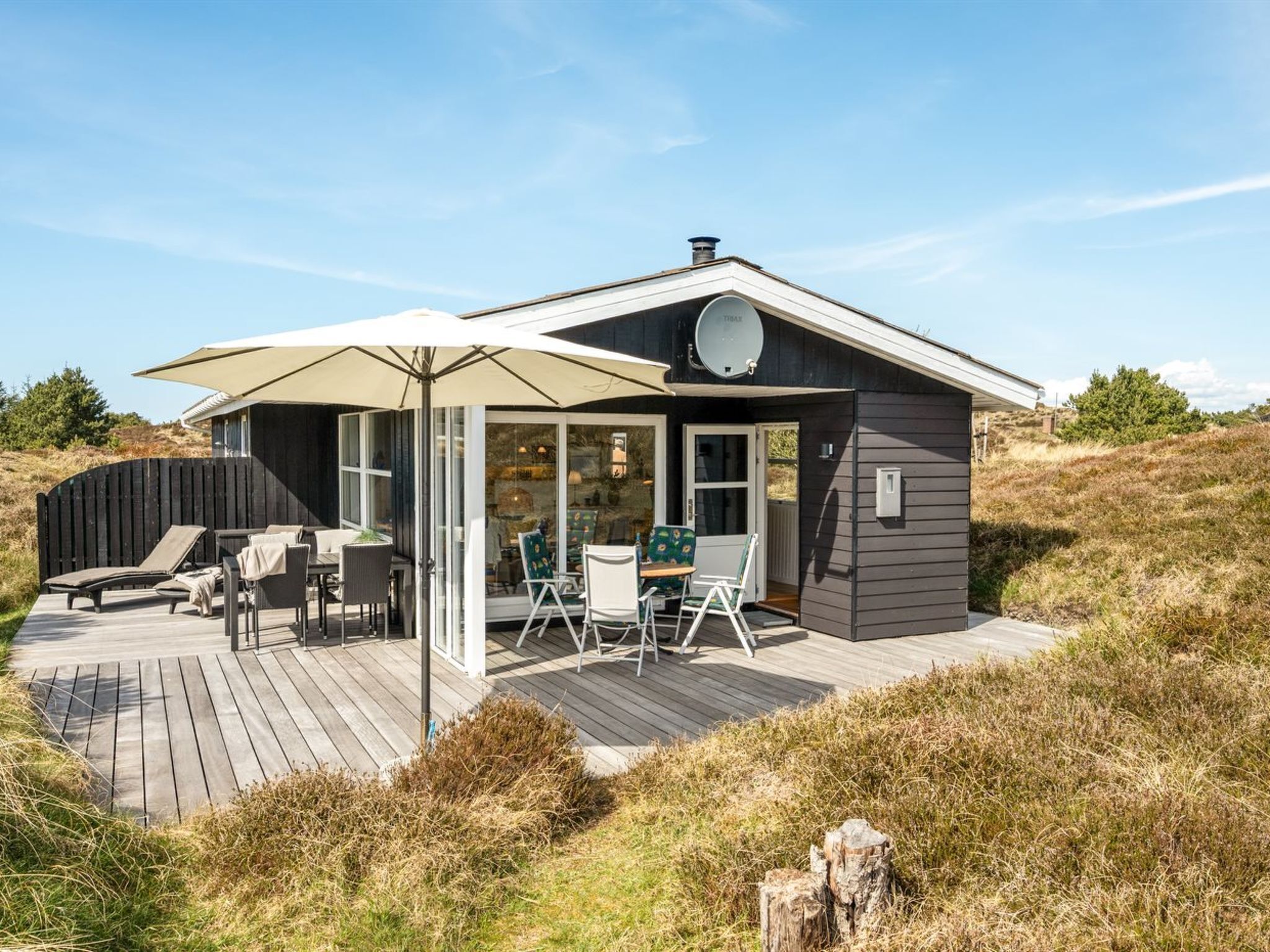 Una casa moderna con terraza, mobiliario exterior y antena parabólica.