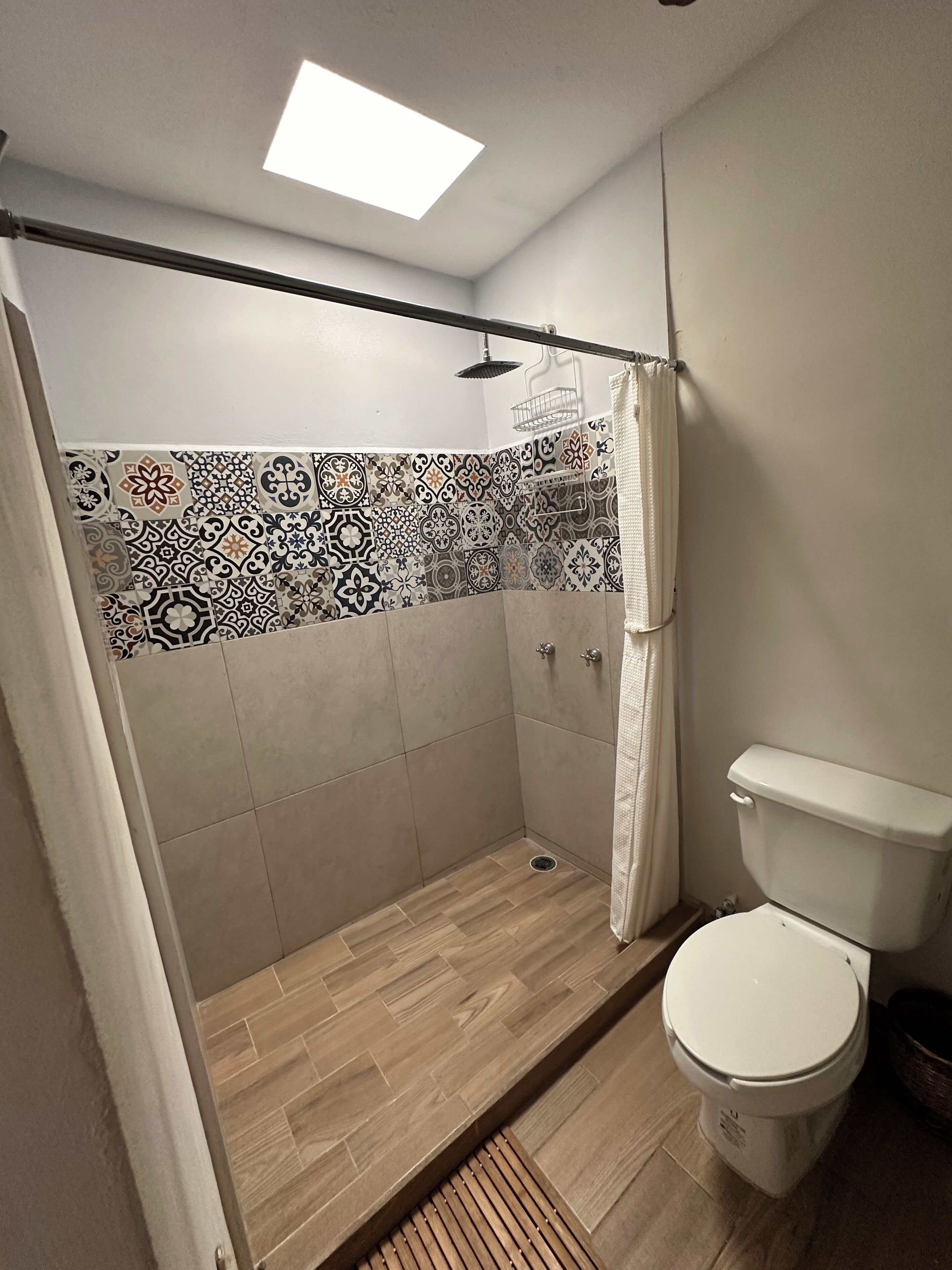 A bathroom with a shower, toilet, and patterned tiles.