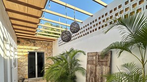 A covered patio area with a stone wall, potted plants, and a wooden door. - Casa Colonial en el Centro de Mérida, Remodelada, Excelente Para Grupos Grandes (Centro)