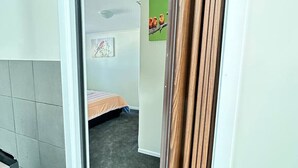 Ein schmaler Flur mit einem Bett und einem Bild an der Wand.
