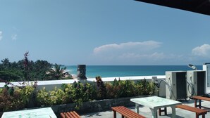 Una terraza con vistas al océano, mobiliario exterior y una estatua.