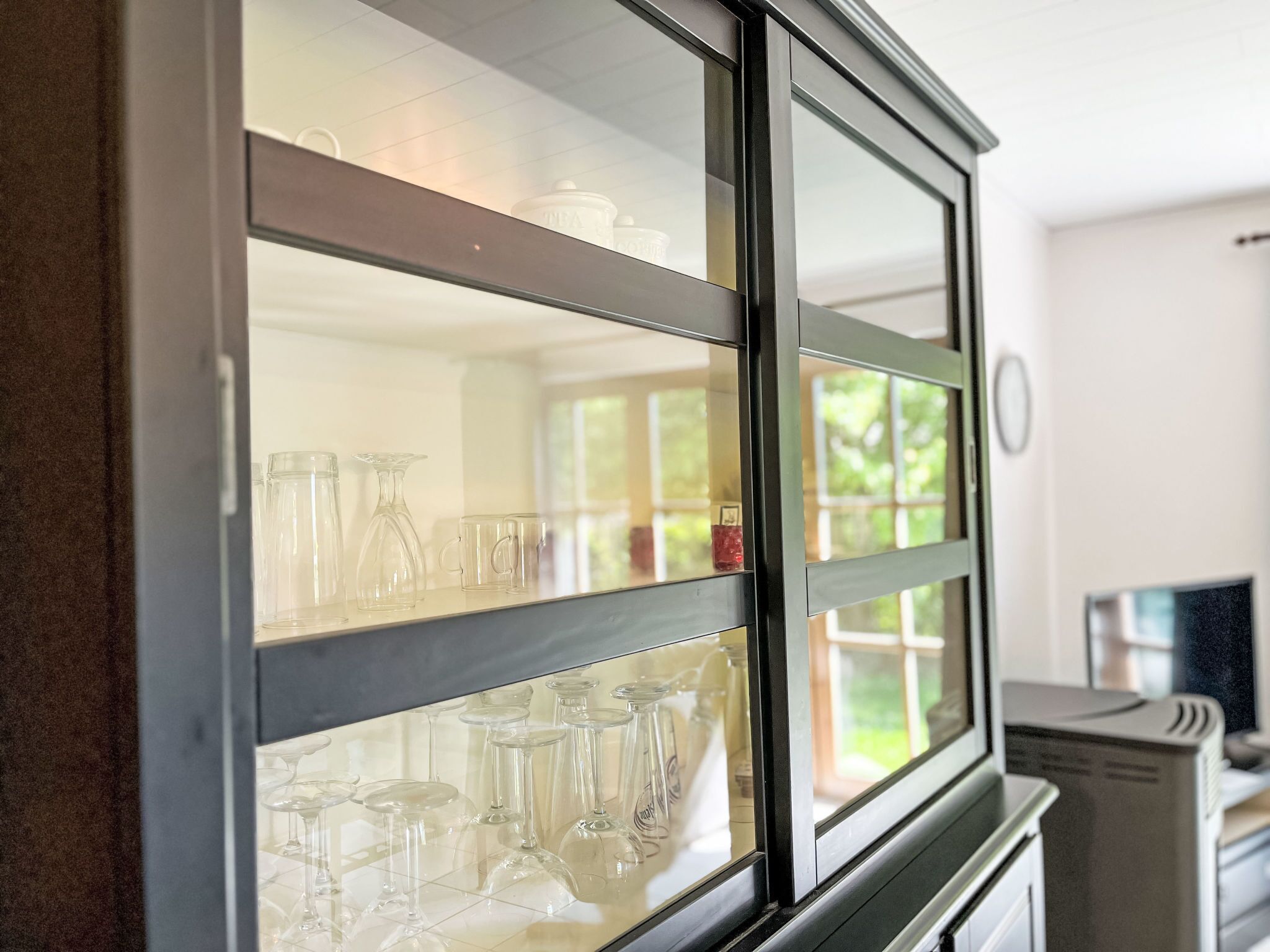 A kitchen with a glass-fronted cabinet displaying various glassware.