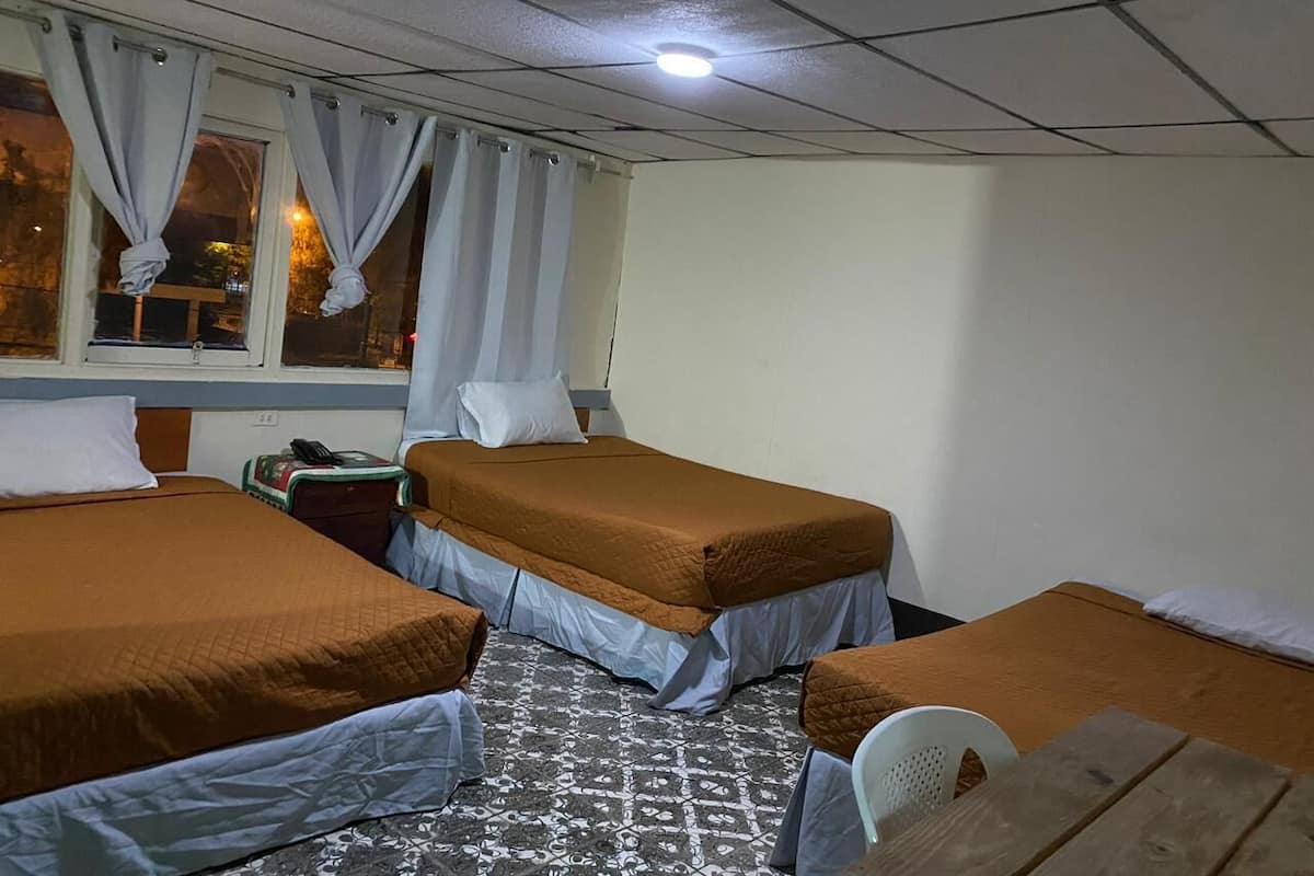A room with two beds, a small table, and a window with curtains.