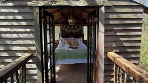 Una cabaña de troncos con una cama, una araña y un letrero que dice 'Feliz Aniversario'.