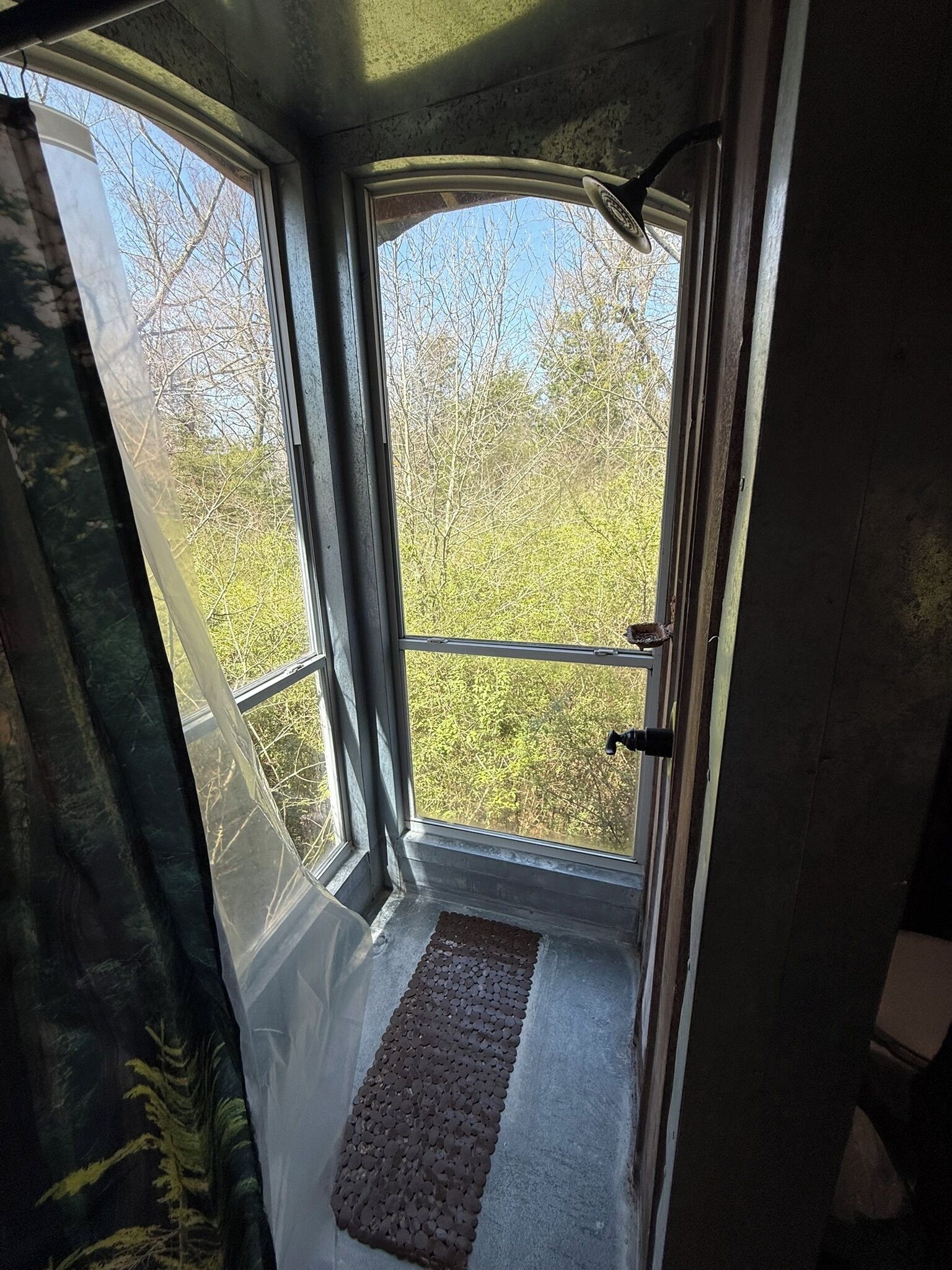 A room with a large window, a door, and a small mat at the entrance.