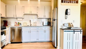 A modern kitchen with white cabinets, stainless steel appliances, and a wooden countertop. - Riley's Retreat - Resort Pool/HotTub/Ski/Sled/Tube (Beech Mountain)