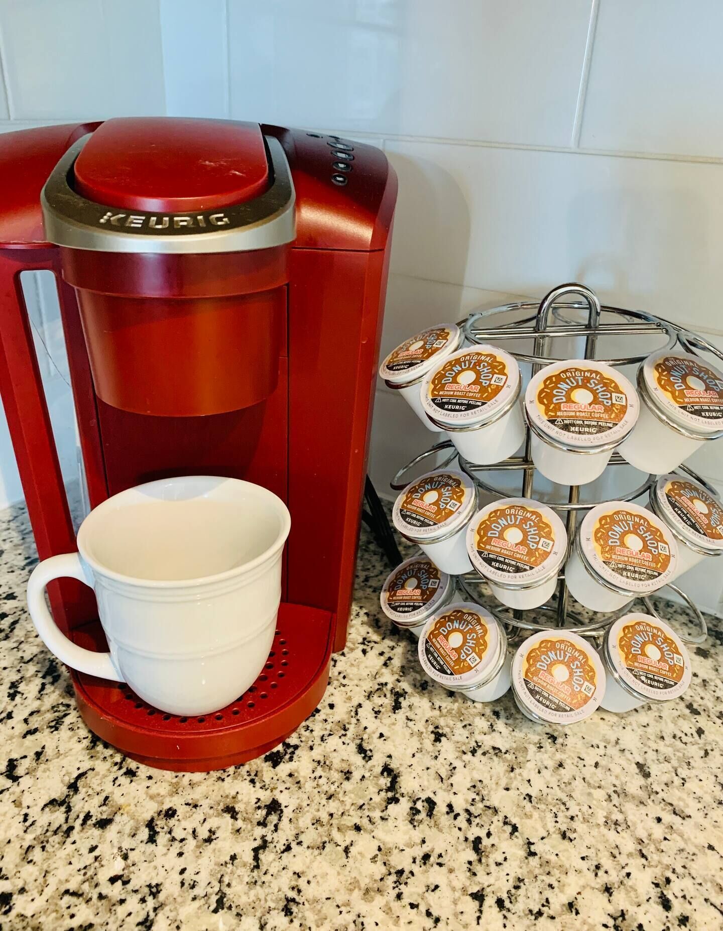Een rode Keurig koffiezetapparaat met een witte mok en een bakje Keurig koffiekapsules.